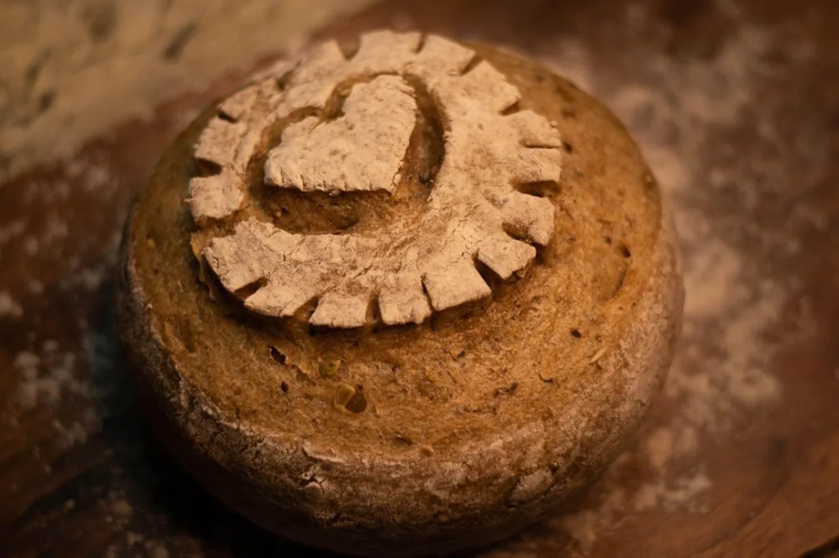 Manos sosteniendo pan campesino con corazón grabado